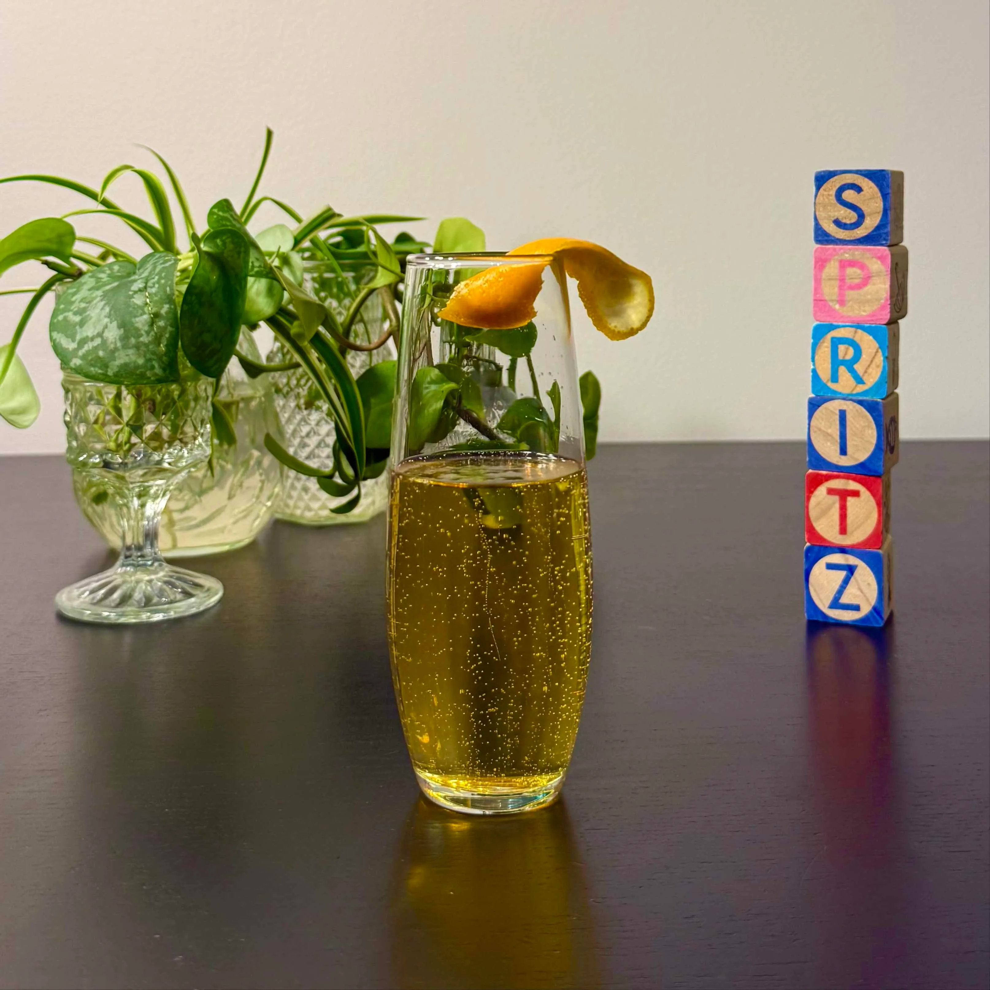 Golden, bubbly Cinnamon Sparkler cocktail in a stemless champagne flute garnished with an orange peel twist