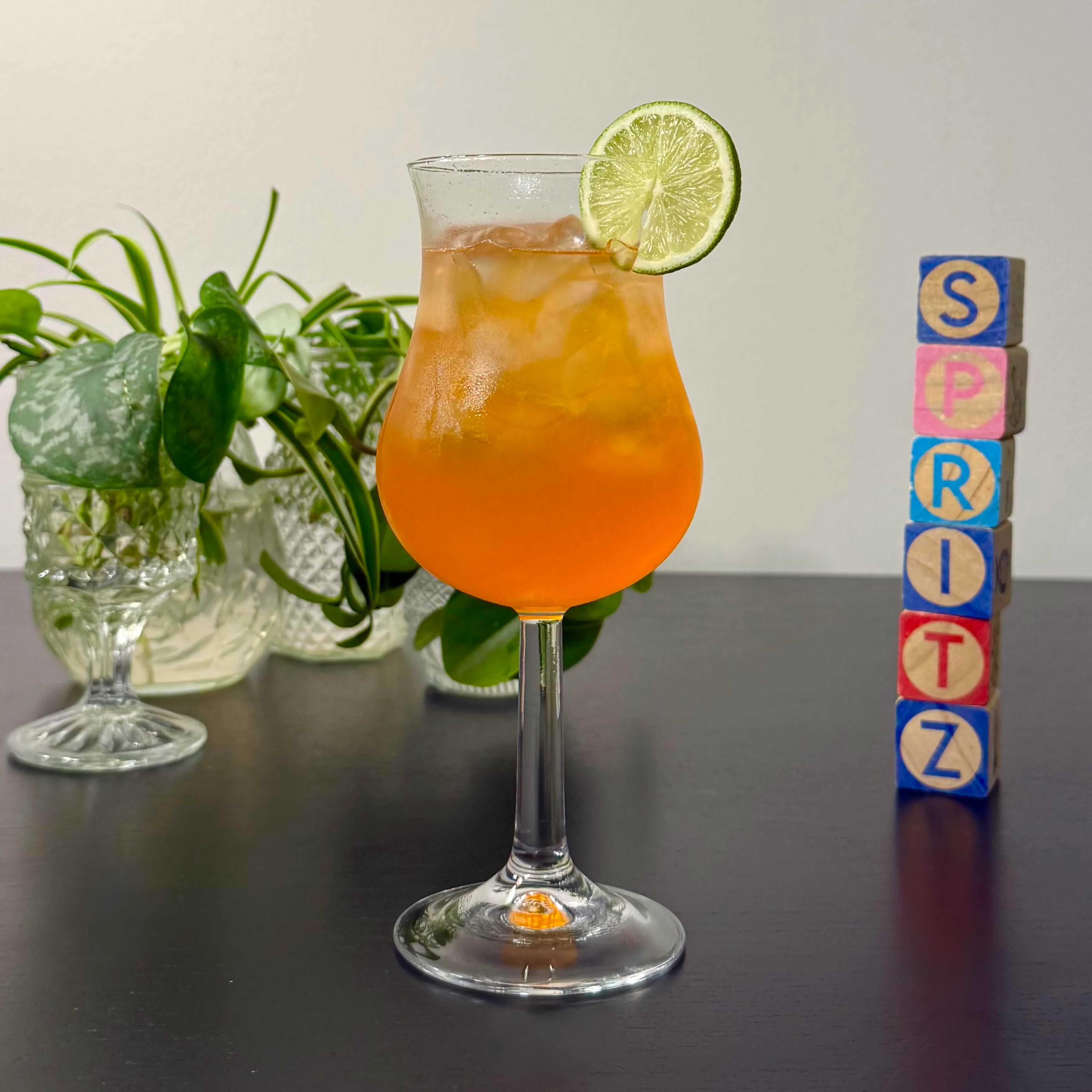 Tropical Rum Spritz of rum, Aperol, and soda water over ice in a tulip-shaped glass garnished with a lime wheel